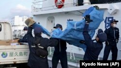 The members of Japanese Coast Guard carry the debris which are believed to be from the crashed U.S. military Osprey aircraft, at a port in Yakushima, Kagoshima prefecture, southern Japan, Dec. 4, 2023.