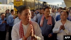 FILE - Cambodian Minister of Public Works and Transport Sun Chanthol, center left, and tycoon Kith Meng, right, chairman of The Royal Group gestures on arrival in Phnom Penh railway station on July 4, 2018.