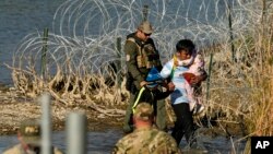 FILE - Migrants are taken into custody by officials at the Texas-Mexico border, in Eagle Pass, Texas, Jan. 3, 2024.