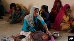 A woman takes care of her child as she with other families take shelter in a school after fleeing from their villages of coastal areas due to Cyclone Biparjoy approaching, in Gharo near Thatta, Pakistan, June 14, 2023. 