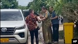 FILE - In this image from a source wishing to remain anonymous, an activist, at left, traveling with Chinese rights lawyer Lu Siwei, right, argues with police who were detaining Lu, near the Thanaleng dry port, south of Vientiane, Laos, July 28, 2023.