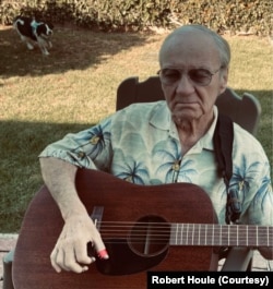 Bob plays his guitar in his backyard in Costa Mesa, California, as one of his Cocker Spaniels roams behind him. 