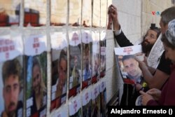 Varias personas colocan carteles con los rostros de los israelíes secuestrados por Hamás en el Muro de las Lamentaciones de Jerusalén.