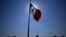 FILE - A Mexican flag waves in front of The National Palace, the office of the president, in Mexico City's main square, the Zocalo, at sunrise, April 24, 2023. 