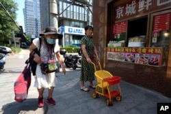 An elderly woman walks by a store selling snacks in Beijing, July 17, 2023.