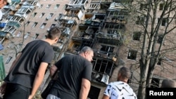 People gather outside of a residential building that according to local authorities was hit by debris from a destroyed Ukrainian missile in Kursk, Russia, Aug. 11, 2024. (Kommersant Photo/Anatoliy Zhdanov via Reuters)