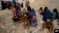 Afghan families wait to board into a bus to depart for their homeland, in Karachi, Pakistan, Oct. 6, 2023.