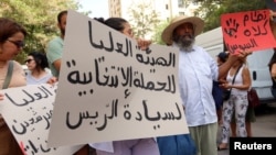 Demonstrators carry banners during a protest demanding the implementation of a ruling by the administrative court to reinstate three presidential candidates, near the headquarters of the Electoral Commission in Tunis, Tunisia, Sept. 2, 2024.