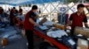 FILE - Delivery workers sort packages on a conveyor belt, ahead of a shopping festival at a logistics station in Beijing, June 12, 2023. 