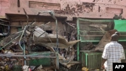 People walk past a medical center building riddled with bullet holes at the Souk Sitta (Market Six) in the south of Khartoum, Sudan, on June 1, 2023.