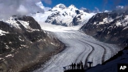 FILE - People enjoy the view at the Aletsch Glacier near Goms, Switzerland, on June 14, 2023. Swiss glaciers have lost 10% of their volume since 2021, and some glaciers are predicted to disappear entirely in the next few years.