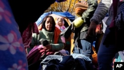 Migrant women from Venezuela look over new clothes, Wednesday, Nov. 1, 2023, outside a Northside police station where they live in a small tent community in Chicago. (AP Photo/Charles Rex Arbogast)
