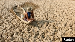 រូបឯកសារ៖ បុរសនេសាទម្នាក់អង្គុយលើទូកនៅក្នុងបឹងដែលរីងស្ងួត ក្នុងអំឡុងគ្រោះរាំងស្ងួត នៅខេត្តកណ្តាល កាលពីថ្ងៃទី ១៣ ខែឧសភា ឆ្នាំ ២០១៦។ 