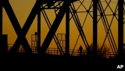 A man walks across the Puente Negro Ferrocarril rail bridge that connects Mexico and the US, Jan. 3, 2024, in Eagle Pass, Texas.