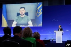 Ukraine's President Volodymyr Zelenskyy attends through video link as British Prime Minister Rishi Sunak looks on during the Ukraine Recovery Conference in London, June 21, 2023.