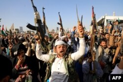 Houthi fighters brandish weapons during a protest following U.S. and British forces strikes, in the Houthi-controlled capital of Sanaa, Jan. 12, 2024.
