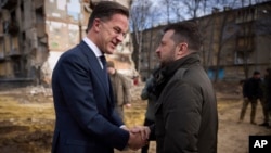 In this photo provided by the Ukrainian Presidential Press Office, President Volodymyr Zelenskyy, right, and Netherlands Prime Minister Mark Rutte talk near apartment houses damaged in Russian missile attacks in Kharkiv, Ukraine, March 1, 2024.