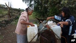 FILE - Emilia Segura, left, and her daughter Cecilia Rivera Segura arrange containers after filling them with water at a free, public well in Pueblo Santa Cruz Acalpixca, Xochimilco, on the outskirts of Mexico City, Oct. 7, 2023.