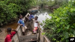 Children sit inside a fishing boat outside a mangrove in Kimpozia village, one of the areas auctioned for oil drilling, in Moanda, Democratic Republic of the Congo, Monday, Dec. 25, 2023. (AP Photo/Mosa'ab Elshamy)
