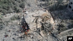 Orang-orang Palestina mencari para korban yang masih hidup setelah pengeboman oleh Israel di Deir Al-Balah, Jalur Gaza, 22 Oktober 2023. (Foto: Hatem Moussa/AP Photo)