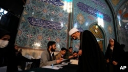 Seorang ulama menerima surat suara ketika menggunakan hak pilihnya dalam pemilu parlemen dan Majelis Ahli Iran, di sebuah tempat pemungutan suara di Teheran, pada 1 Maret 2024. (Foto: AP/Vahid Salemi)