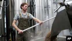 FILE - Brewer Scott Peterson retrieves spent grain from a lauterton while brewing a German-style Pilsner at Von Ebert Brewing in Portland, Ore., Oct. 22, 2023.
