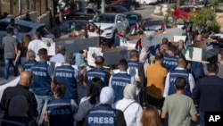 Palestinian journalists carry mock coffins of colleagues killed during the current Israel-Hamas war, during a symbolic funeral procession toward a United Nations office in the West Bank city of Ramallah, Nov. 7, 2023.