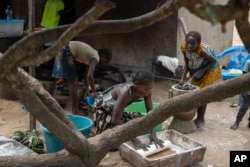 A family bakes bread in their village of Kinkazi, which has been impacted by oil drilling, outside Moanda, Democratic Republic of the Congo, Sunday, Dec. 24, 2023. (AP Photo/Mosa'ab Elshamy)