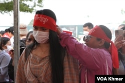 អ្នកចូលរួមក្នុងពិធីអបអរទិវាអន្តរជាតិនារីលើកទី១១៣ ជួយគ្នាពាក់ក្រណាត់ចងរុំក្បាលពណ៌ក្រហមសរសេរថា «ជីវិតថ្លៃថ្នូរ» នៅទីលានប្រជាធិបតេយ្យ ក្នុងរាជធានីភ្នំពេញ នាថ្ងៃទី៨ ខែមីនា ឆ្នាំ២០២៤។ (ស៊ឹម ចាន់សំណាង/វីអូអេ)