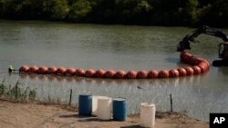FILE - Workers deploy a string of large buoys to be used as a border barrier at the center of the Rio Grande near Eagle Pass, Texas, July 11, 2023. The floating barrierwas deployed in an effort to block migrants from entering Texas from Mexico. 