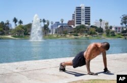 Un hombre hace ejercicio sin camisa a medida que aumentan las temperaturas en MacArthur Park, el martes 11 de julio de 2023 en Los Ángeles. Los Ángeles espera altas temperaturas entre 100 y 110 grados Fahrenheit a finales de esta semana según el Servicio Meteorológico Nacional. (Foto AP/Marcio José Sánchez)