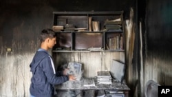 Ali Fawaz checks destroyed books and notebooks inside his damaged family house that was hit by Israeli shelling in the Kfar Kila border village with Israel in south Lebanon, Nov. 25, 2023. 