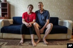 Nataliia Skakun and her husband Serhii, former residents of Oleshky, Ukraine, sit on a sofa at their apartments in Mykolaiv, Ukraine, Tuesday, July 4, 2023.