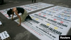 ARCHIVO - Un defensor de los derechos humanos coloca una pancarta con los nombres de las víctimas de los paramilitares colombianos durante una manifestación frente a la embajada de Costa Rica en Bogotá el 22 de abril de 2008.