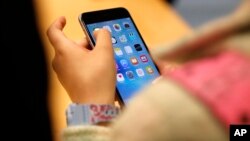 FILE - In this Sept. 25, 2015, photo, a young person tries out an iPhone at an Apple store in Chicago. A new study released March 11, 2024, says three-quarters of U.S. teens say they feel happy or peaceful when they don't have their phones with them.