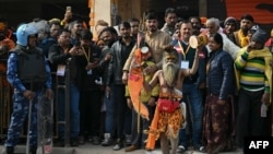 A sadhu or Indian holy man holds a trident with a flag with picture of Hindu deity lord Ram, along a road in Ayodhya on Jan. 22, 2024.