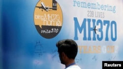 រូបឯកសារ៖ បុរសម្នាក់​សរសេរ​សារ​នៅ​លើ​ផ្ទះ​ដែល​ឧទ្ទិស​ដល់​ជនរងគ្រោះ​នៃ​ការ​បាត់​យន្តហោះ MH370 នៅ​ទីក្រុង​គូឡាឡាំពួ ប្រទេស​ម៉ាឡេស៊ី កាលពីថ្ងៃទី៣ ខែមីនា ឆ្នាំ២០១៩។ 