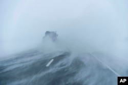 A truck moves along the snow-blown eastbound lane of US Highway 20 during a blizzard near Sac City, Iowa, Jan. 13, 2024.