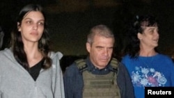 Judith Tai Raanan and daughter Natalie Shoshana Raanan, U.S. citizens who were Hamas hostages, walk with retired Brig. Gen. Gal Hirsch, Israel's coordinator for the captives and missing, after their release, in this handout picture, Oct. 20, 2023.