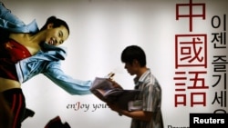 FILE - A South Korean walks past a billboard of a Chinese language institute in Seoul, July 6, 2004. The number of South Koreans studying in China has dropped dramatically in recent years.