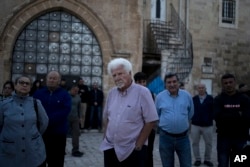 FILE - Garo Nalbandian, an 80-year-old photojournalist, center, listens to a speaker during an Armenian community protest of a contentious deal that stands to displace him and other residents of the Armenian Quarter in the Old City of Jerusalem, May 19, 2023.