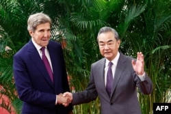 FILE - US Climate Envoy John Kerry and Director of the Office of the Foreign Affairs Commission of the Communist Party of China's Central Committee Wang Yi shake hands before a meeting at the Great Hall of the People in Beijing, July 18, 2023.