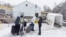 FILE - A family crosses into Canada at Roxham Road, an unofficial crossing point from New York state to Quebec for asylum-seekers, in Champlain, N.Y., March 25, 2023. 