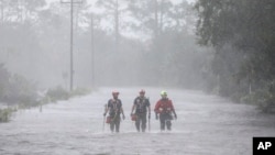 FILE - Rescue workers wade through a tidal surge on a highway while looking for people in need of help after the Steinhatchee River flooded, Aug 30, 2023, in Steinhatchee, Fla., following the arrival of Hurricane Idalia. 