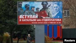 FILE - A local resident walks past a billboard encouraging men to join a Russian battalion amid Moscow's war on Ukraine, in Melitopol, Russian-occupied Ukraine, Nov. 27, 2022. Three Russian officers were reportedly killed in an attack Saturday on a local military headquarters.