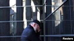 A man reacts in front of a wall bearing the names of victims during a ceremony marking International Holocaust Remembrance Day at the Holocaust Memorial Center in Budapest, Hungary, Jan, 26, 2024. 
