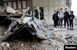 A Palestinian man and children inspect the site of an Israeli strike on a car in Nablus, in the Israeli-occupied West Bank, Jan. 17, 2024.