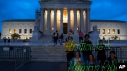 Demonstrators mark anniversary of Supreme Court decision in Dobbs v. Jackson Women's Health Organization, which overturned Roe v. Wade, with a neon sign, June 23, 2023, Washington.