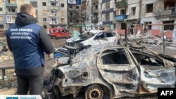 ২০২৪ সালের ১০ মার্চ ডনেটস্ক অঞ্চলের প্রসিকিউটর কার্যলয় কর্তৃক তোলা এই ছবিটি ডনেটস্ক অঞ্চলের মিরনোহরাদে একটি ক্ষেপণাস্ত্র হামলার পর একজন যুদ্ধাপরাধ প্রসিকিউটরকে দেখা যাচ্ছে।