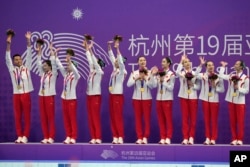 Gold medalist Team China celebrates on the podium during the victory ceremony for the team free routine artistic swimming at the 19th Asian Games in Hangzhou, China, Oct. 8, 2023.